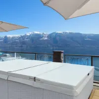 Piscina Laghetto playa coperta da Winter Cover Playa. sullo sfondo si vedono vette di montagne innevate. La piscina è rivestita in rattan bianco ela copertura Winter Cover è in Sky nautico colore natural.