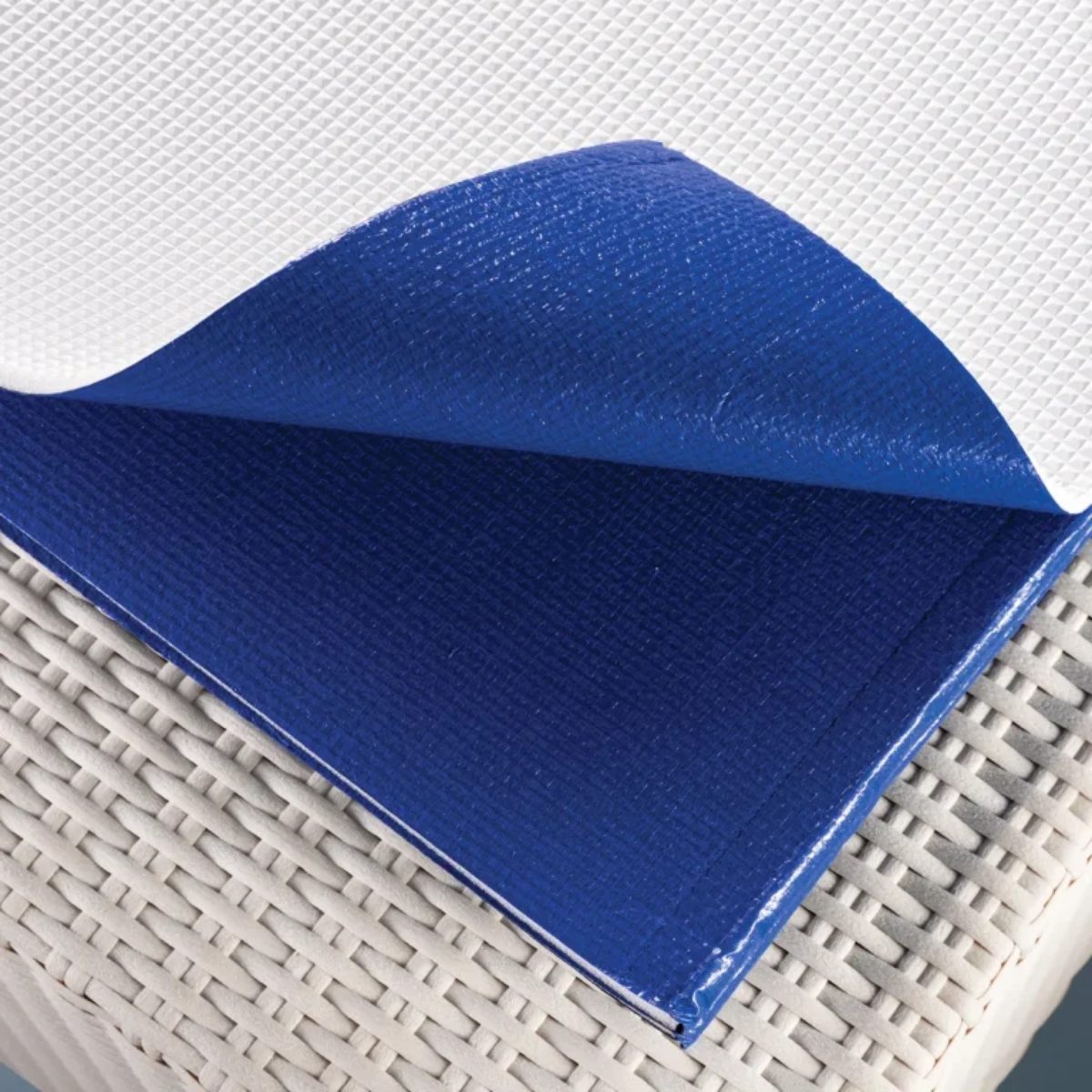 Telo Isotermico per piscina Laghetto Playa In primo piano di un telo isotermico per piscina, piegato su un piano intrecciato chiaro, probabilmente in rattan o vimini. L'immagine è luminosa e pulita, con una messa a fuoco nitida sul telo isotermico. La composizione è semplice e diretta, con l'obiettivo di mostrare la texture e i colori del telo. L'immagine trasmette una sensazione di ordine e funzionalità, tipica di un prodotto progettato per la cura e la manutenzione della piscina.