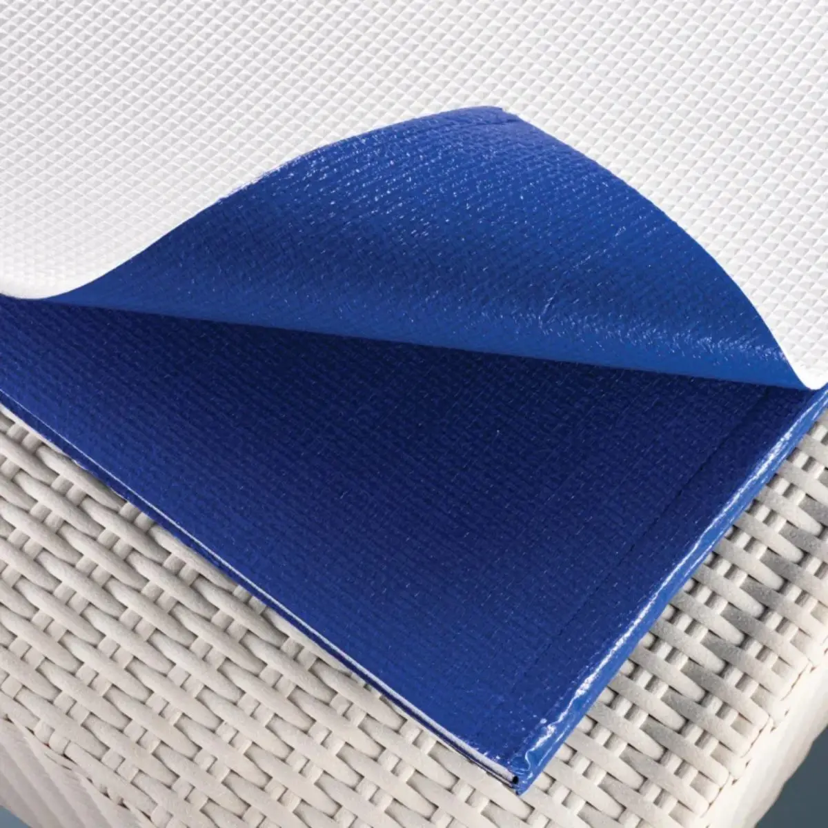 Telo Isotermico per piscina Laghetto Playa In primo piano di un telo isotermico per piscina, piegato su un piano intrecciato chiaro, probabilmente in rattan o vimini. L'immagine è luminosa e pulita, con una messa a fuoco nitida sul telo isotermico. La composizione è semplice e diretta, con l'obiettivo di mostrare la texture e i colori del telo. L'immagine trasmette una sensazione di ordine e funzionalità, tipica di un prodotto progettato per la cura e la manutenzione della piscina.