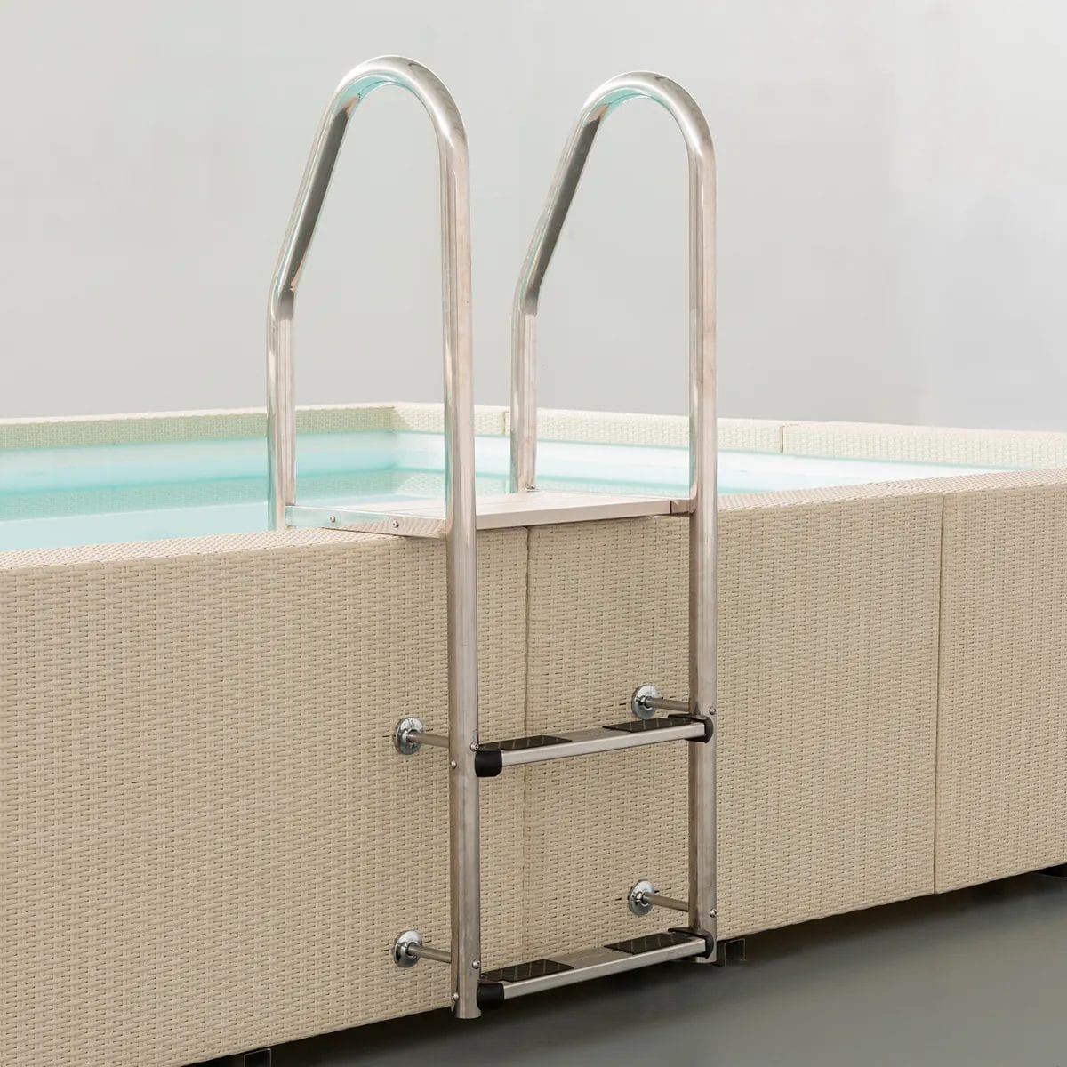 Piscina fuori terra Laghetto Divina con rivestimento in fibra sintetica intrecciata effetto rattan colore bianco, particolare scaletta in acciaio inoxvista dall'esterno della piscina
