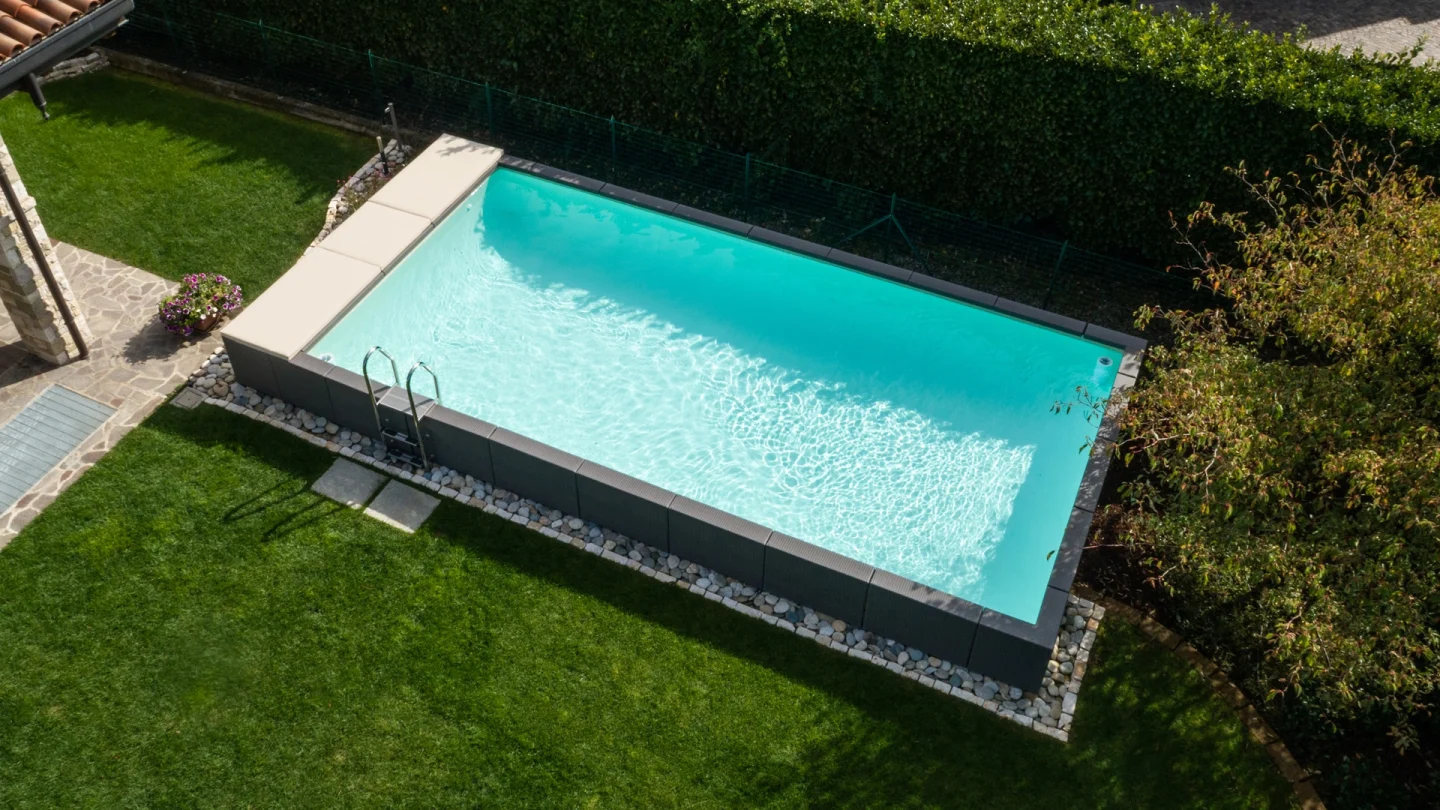 Piscina fuori terra Laghetto Divina con rivestimento in fibra sintetica intrecciata effetto rattan colore grigio. Presentata in un contesto outdoor elegante, vista dall'alto