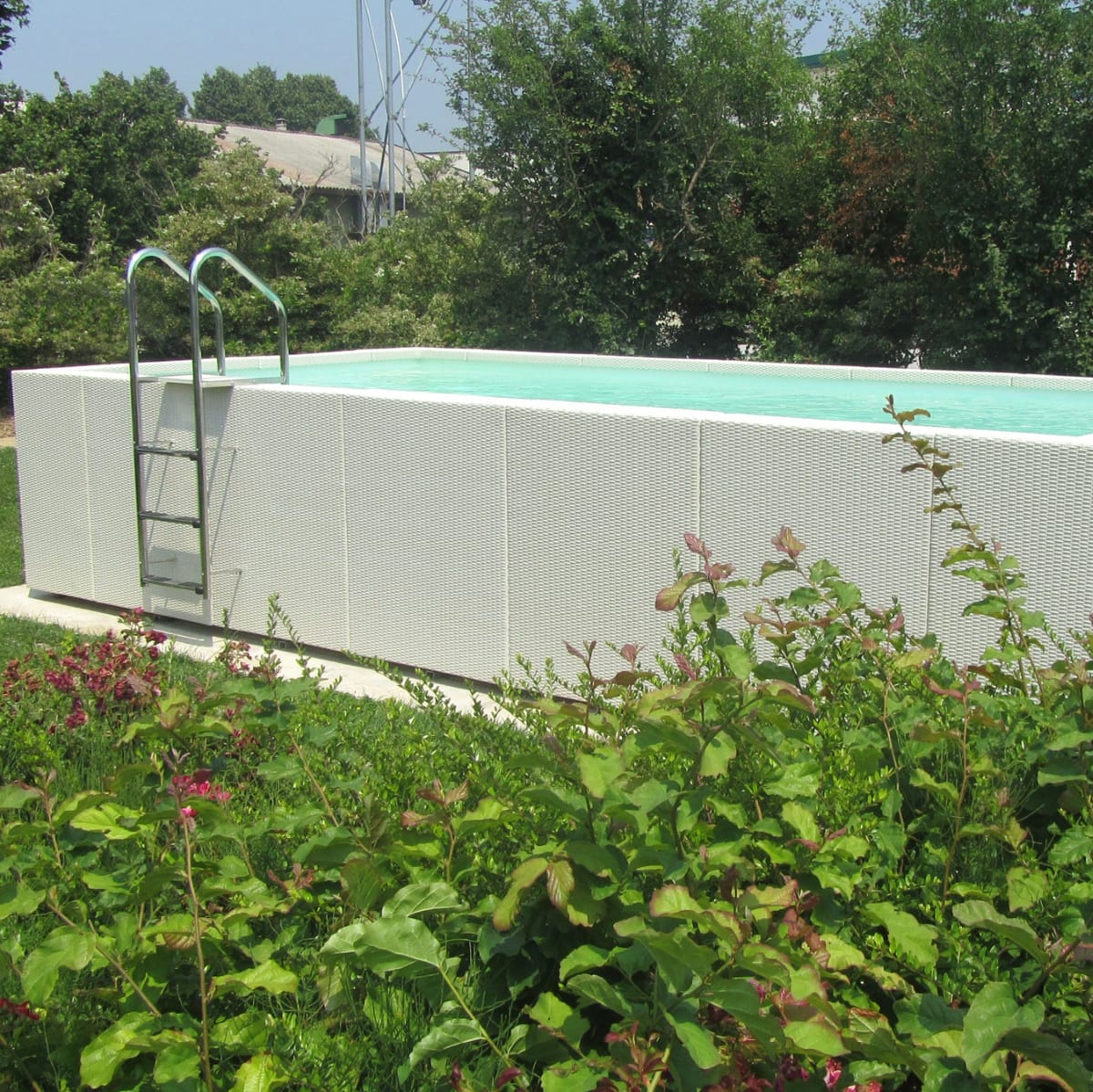 Piscina fuori terra Laghetto Dolcevita Diva LTI con rivestimento in fibra sintetica intrecciata effetto rattan colore bianco. Presentata in un contesto outdoor naturale.