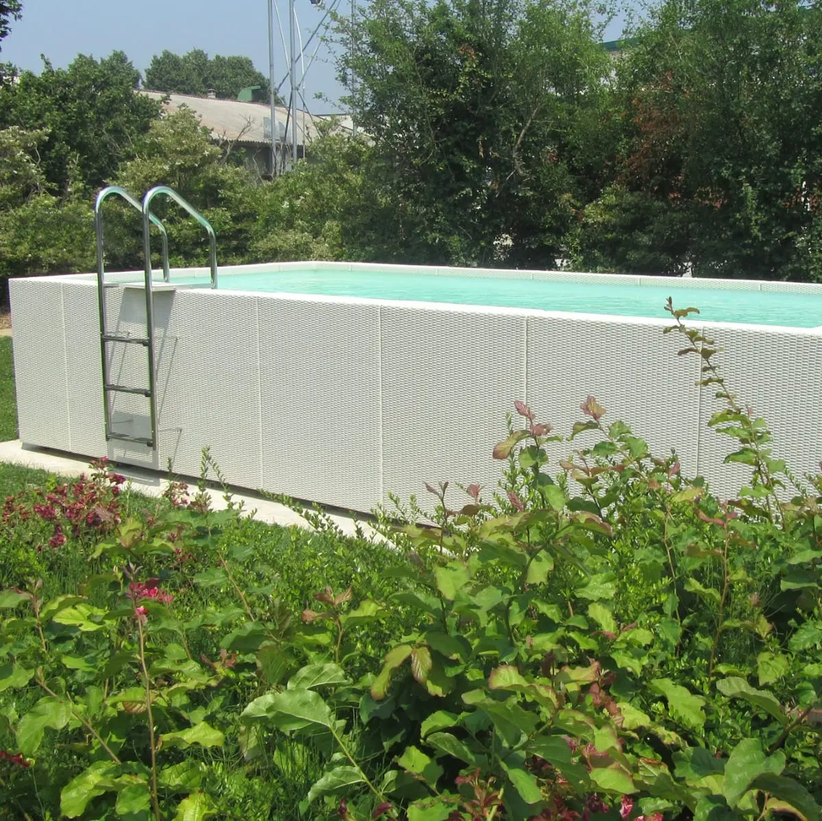 Piscina fuori terra Laghetto Dolcevita Diva LTI con rivestimento in fibra sintetica intrecciata effetto rattan colore bianco. Presentata in un contesto outdoor naturale.