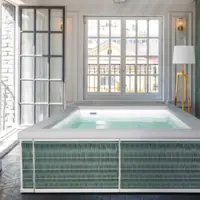 Piscina fuori terra Laghetto Ninfea Thiny con rivestimento in corda. Presentata in un terrazzo indoor. Colore rivestimento Olive Green, colore cuscino bianco.