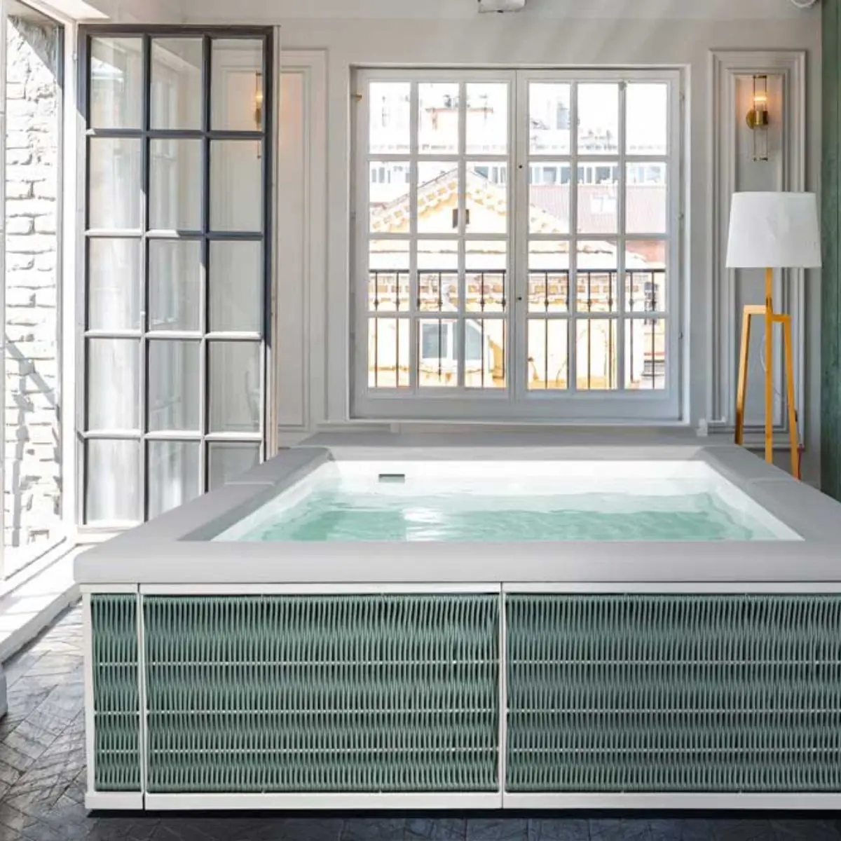 Piscina fuori terra Laghetto Ninfea Thiny con rivestimento in corda. Presentata in un terrazzo indoor. Colore rivestimento Olive Green, colore cuscino bianco.