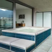 Piscina fuori terra Laghetto Ninfea Thiny con rivestimento in corda. Presentata in un terrazzo outdoor. Colore rivestimento Deep Blue, colore cuscino bianco.